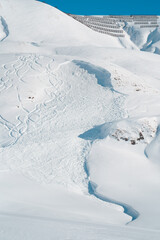 Freshly triggered slab avalanche in a snowy mountain landscape, caused by skiers venturing off secured slopes