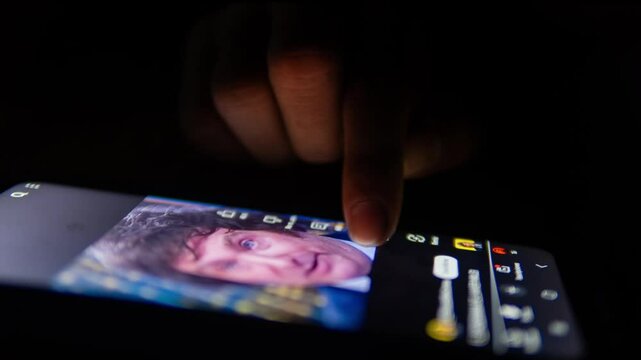 Finger scrolling through social media feed on smartphone at night