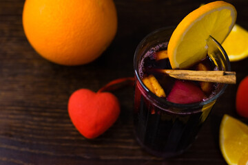 Delicious mulled wine with orange, cinnamon and honey in a glass and decorative red hearts on a...