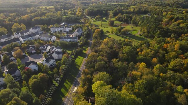 Aerial view of residential street and forest along road with fall colors of nature,
