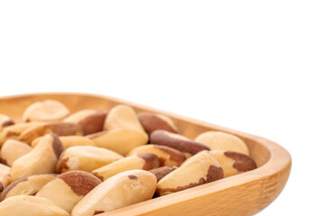 Brazil nuts without shells on a bamboo tray, macro, on a white background.