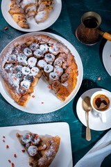 Traditional homemade banana caramel pie. French Tarte Tatin on a white plate with Turkish coffee on a green, emerald background.Top view