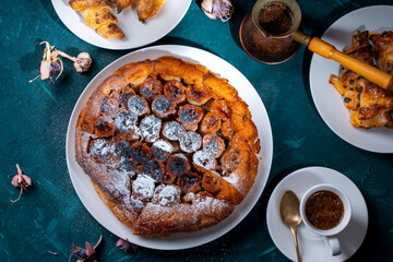 Traditional homemade banana caramel pie. French Tarte Tatin on a white plate with Turkish coffee on a green, emerald background.Top view
