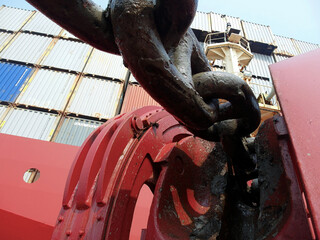 Anchor chain and red forward starboard side mooring winch and anchor windlass of cargo container vessel during passing Atlantic ocean viewed from low angel. 