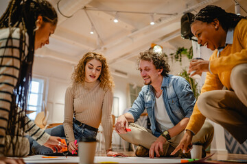 Fototapeta premium multicultural colleagues gather around a large paper on a wooden floor
