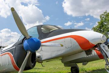 White propeller airplane standing on a grass. Blue sky with clouds is on the background.....