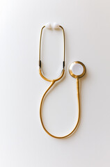 Gold stethoscope on a white background.Minimal creative medical concept.Copy space,flat lay 