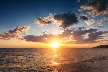 Obraz premium Panoramic beach landscape. Royalty high-quality free best stock of a beautiful sunrise over the ocean with golden sunlight reflecting. Dramatic sky, sense of calm and tranquility