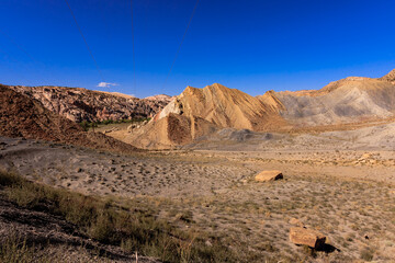 A barren desert landscape with a few rocks and a blue sky
