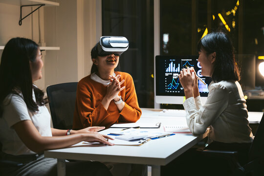 Businesswomen experiencing virtual reality headset during a late night meeting, exploring innovative strategies and data analysis