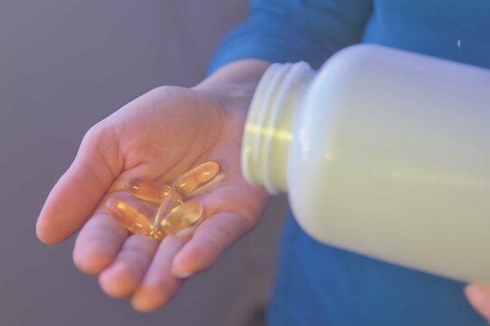 Hand taking vitamins, omega 3, magnesium