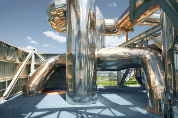 Industrial pipelines glisten in sunlight within a chemical plant showcasing complex engineering and...