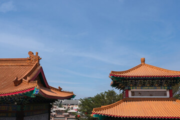 Fototapeta premium Traditional Chinese temple rooftops with ornate designs and vibrant orange tiles stand against a clear blue sky, highlighting the beauty of cultural architecture and craftsmanship.