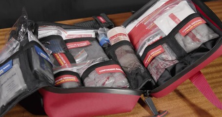 A red first aid kit on a wooden table highlights emergency readiness