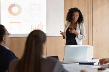 Serious confident African American speaker giving training seminar to team of coworkers, speaking...
