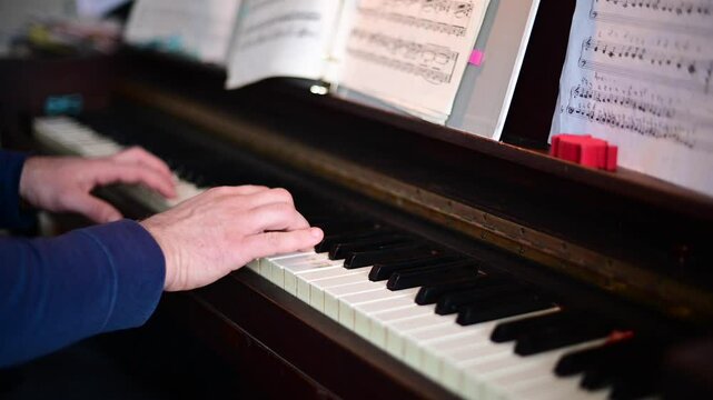 selective focus close up of man hend playing on a old piano
