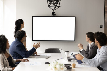 Diverse business team of colleagues meeting at table offline, looking at blank large wall screen...