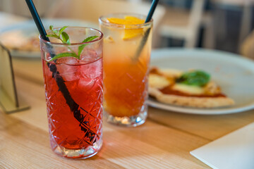 Two mocktails, Cinderella with grenadine and raspberry lemonade, on a wooden table in soft focus. 