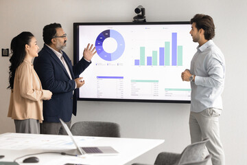 Diverse different aged business partners discussing project marketing research results on large...