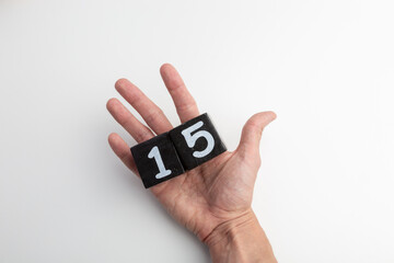 Hand Holding Wooden Blocks Showing Numbers One and Five on White Background