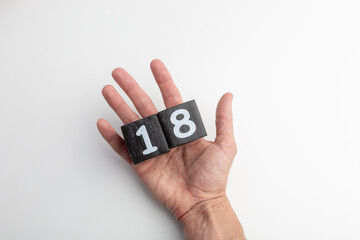 Fototapeta premium Hand Holding Wooden Blocks Showing Numbers One and Eight on White Background