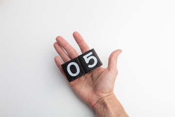 Fototapeta premium Hand Holding Wooden Blocks Showing Numbers Zero and Five on White Background