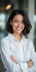 A poised beautiful woman with dark hair, wearing a white shirt, smiles warmly, standing in contemporary office setting filled with natural light, exuding confidence and professionalism. Generative AI.