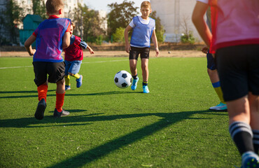 The photo captures a group of young soccer players in colorful jerseys, actively chasing and...