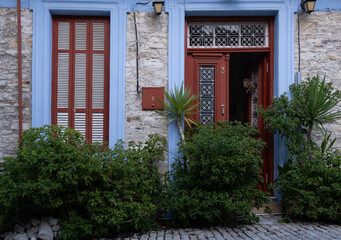 Traditional greek house with red open door and blue window frame