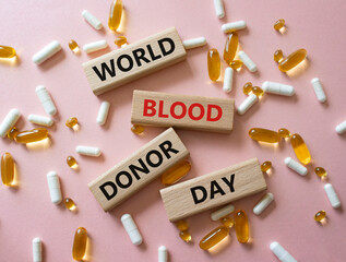 World Blood Donor Day symbol. Concept word World Blood Donor Day on wooden blocks. Beautiful pink background with pills. Medicine and World Blood Donor Day concept. Copy space