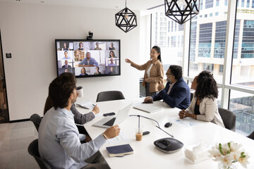 Diverse group of company employees talking to remote colleagues on video conference call chat,...