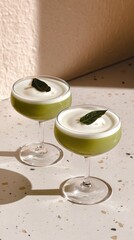 Trendy pandan coconut milk tea in faceted glasses on terrazzo surface with blush backdrop for a fresh and youthful appeal