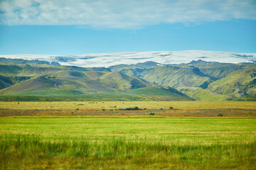 Obraz premium Beautiful nature landscape with green fields and majestic cliffs with ice and snow in Southern Iceland.