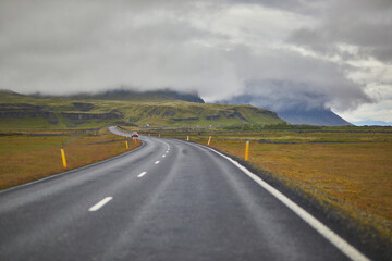 Car driving on a road surrounded by beautiful landscape in Iceland.