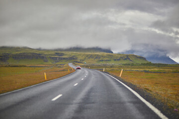 Car driving on a road surrounded by beautiful landscape in Iceland.