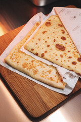 thin pancakes with ham and cheese in an envelope are placed on a serving surface in a restaurant