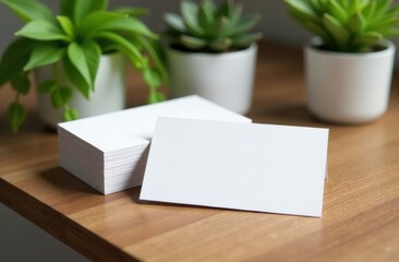 Mock up: white business card on the desktop. Around is a calm modern interior, green house plants. Concept of an eco-friendly workplace, home office. Mockup for business: ecology, realtor, designer, e