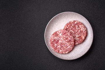 Fresh raw ground beef or pork burger patty with salt and spices