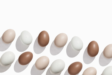 Top view Brown beige Eggs with shadows on light background, minimal trend food pattern from assorted natural Chicken egg with neutral color eggshells, Easter food celebration concept, monochrome