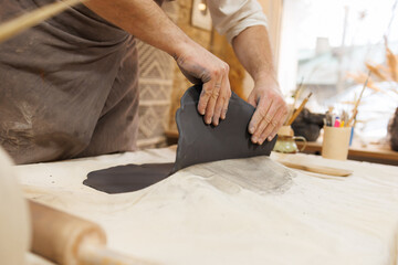 Cropped shot of ceramist taking black clay from cloth in studio