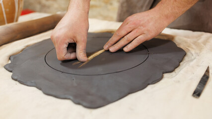 Cropped shot of craftsman pressing wheat spikelet on clay in pottery studio