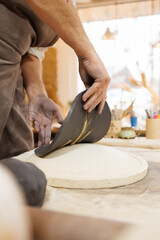 Partial shot of artisan pressing black clay while making plate in studio