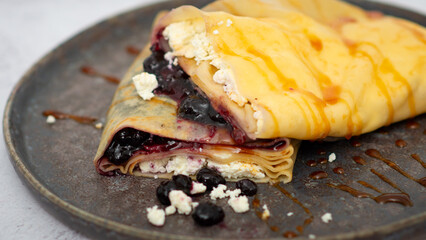 Delicious crepes with cottage cheese, jam, redcurrants and blueberries, closeup