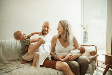 Parents, children and a family laughing on the sofa in the living room of their home together for...