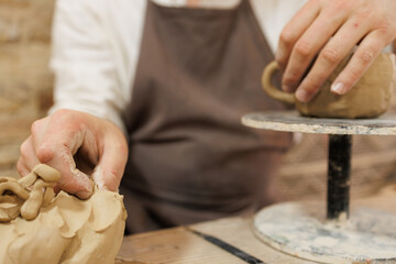 Partial shot of potter taking clay while making cup in studio