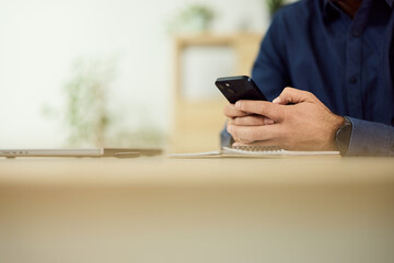 Person Using Smartphone While Working at Office Desk With Notebook and Pencil