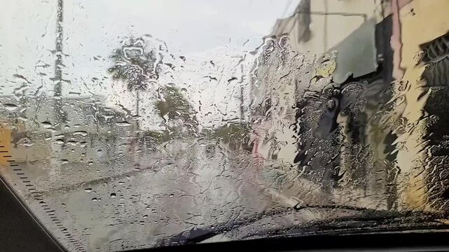 Chuva caindo sobre o para-brisa do carro em uma cidade