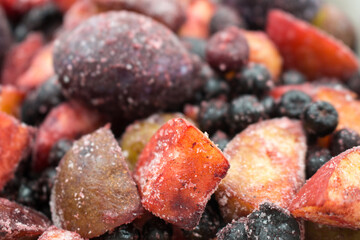 Frozen mixed fruits and berries as background, top view. Black plum, grapes, apples, mountain ash, grapes.