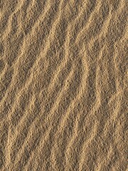 Close-up of golden beach sand with natural waves created by the wind.