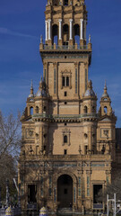 Fototapeta premium A majestic historic tower with intricate architectural details stands against a clear blue sky. Warm-toned bricks, elegant arches, and decorative elements define its grandeur.